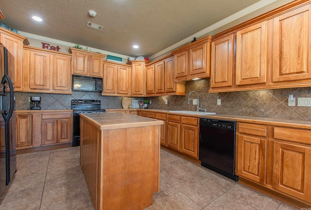 kitchen with sink, crown molding, a center island, light tile patterned floors, and black appliances