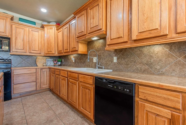 kitchen featuring sink, light tile patterned floors, tile counters, decorative backsplash, and black appliances