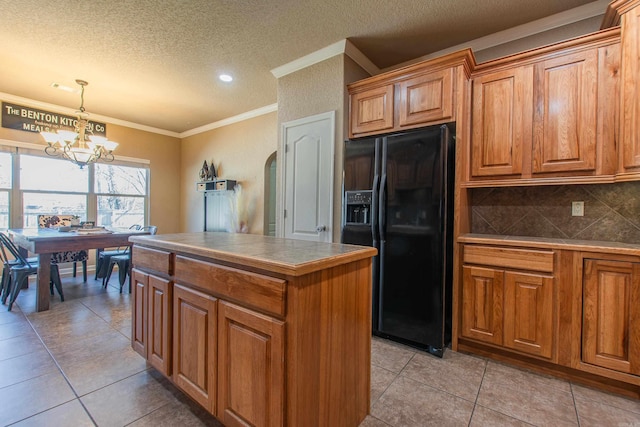 kitchen featuring a kitchen island, backsplash, hanging light fixtures, crown molding, and black fridge