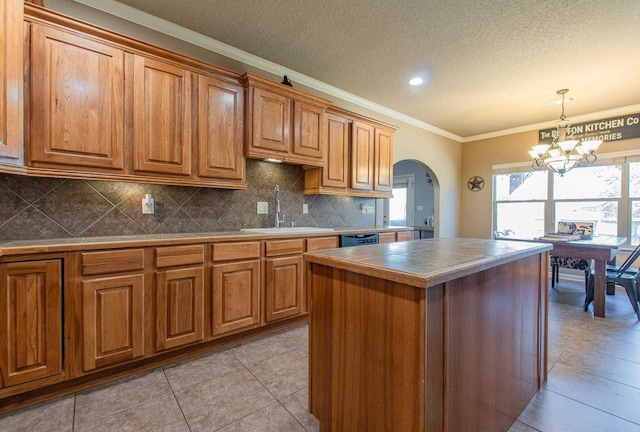 kitchen featuring sink, a center island, light tile patterned floors, ornamental molding, and pendant lighting