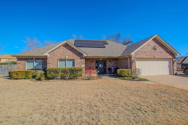 ranch-style home with a garage, a front lawn, and solar panels