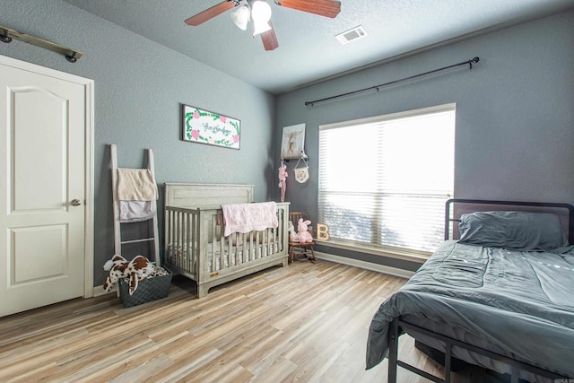 bedroom featuring hardwood / wood-style flooring, a textured ceiling, and ceiling fan