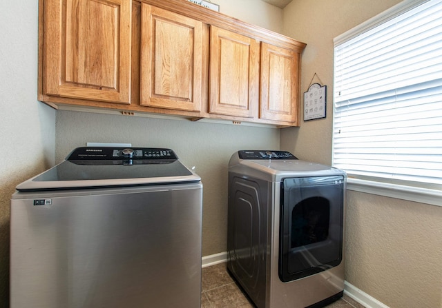 washroom featuring dark tile patterned floors, cabinets, and washing machine and clothes dryer