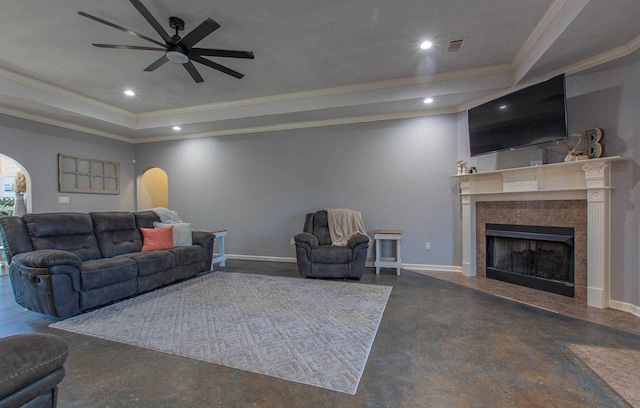 living room featuring crown molding, a fireplace, a raised ceiling, and ceiling fan