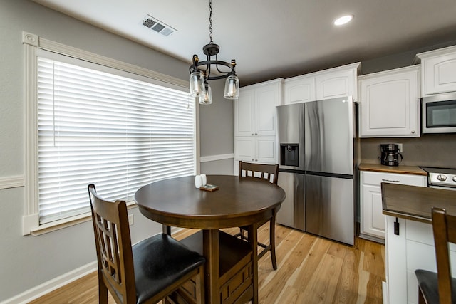 dining room featuring a healthy amount of sunlight, a chandelier, and light wood-type flooring