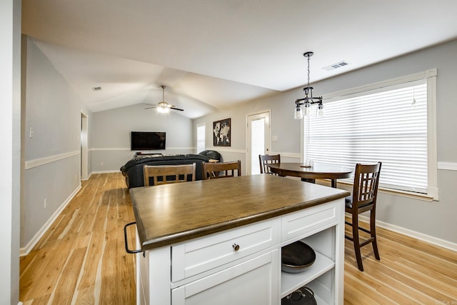 kitchen featuring white cabinetry, hanging light fixtures, vaulted ceiling, and light hardwood / wood-style floors