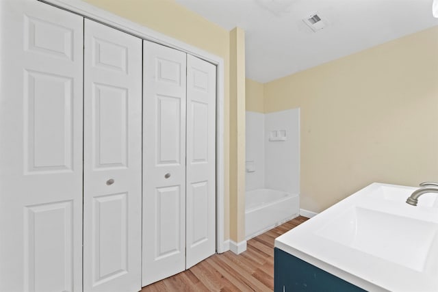 clothes washing area with sink and light hardwood / wood-style floors