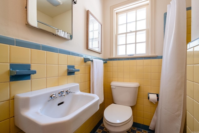 bathroom featuring tile walls and toilet