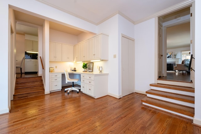 office featuring ornamental molding, built in desk, and light hardwood / wood-style floors