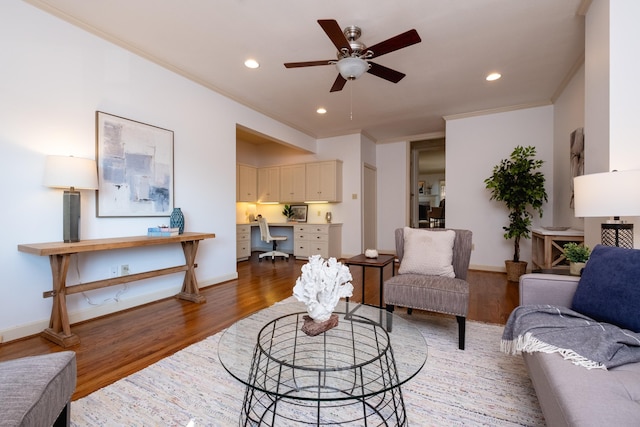 living room featuring ceiling fan, ornamental molding, dark hardwood / wood-style flooring, and built in desk