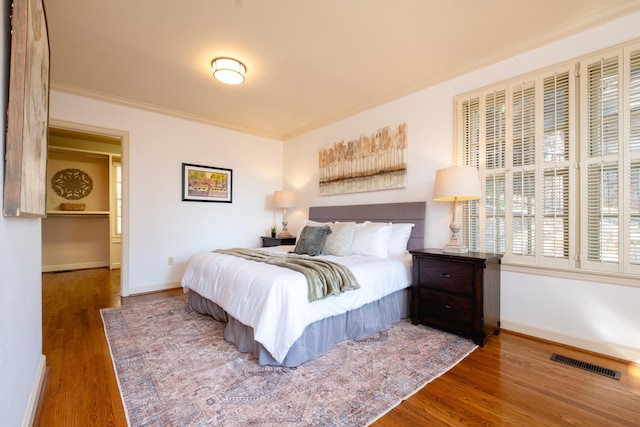 bedroom with dark hardwood / wood-style flooring and ornamental molding