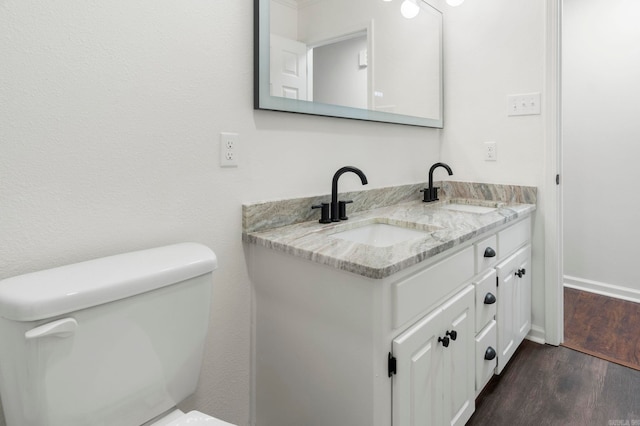 bathroom with wood-type flooring, vanity, and toilet