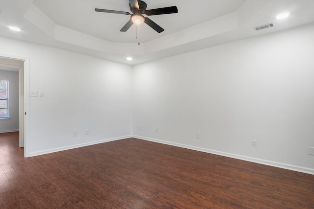 unfurnished room featuring a raised ceiling, ornamental molding, and dark hardwood / wood-style floors