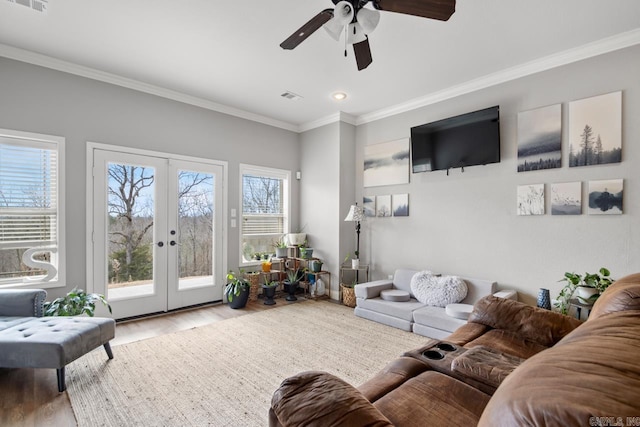 living room with crown molding, light hardwood / wood-style flooring, a wealth of natural light, and french doors