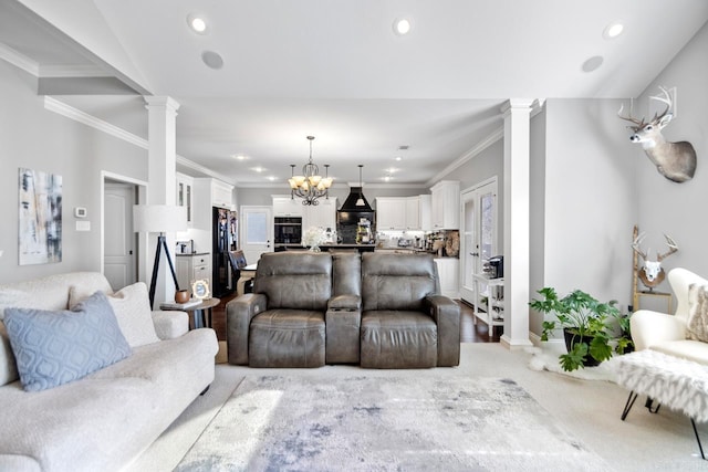 living room featuring light carpet, a notable chandelier, crown molding, and decorative columns