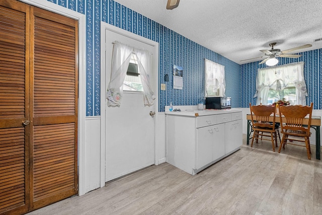 kitchen featuring white cabinets, a textured ceiling, light hardwood / wood-style floors, and ceiling fan