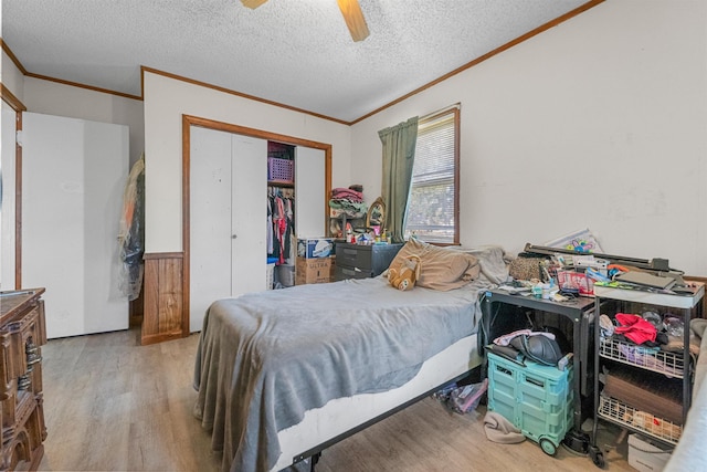 bedroom with ornamental molding, ceiling fan, light hardwood / wood-style floors, a textured ceiling, and a closet