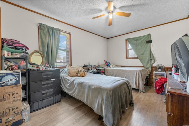 bedroom featuring crown molding, ceiling fan, light hardwood / wood-style flooring, and a textured ceiling