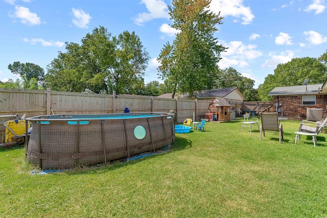 view of yard with a fenced in pool, central air condition unit, and a playground