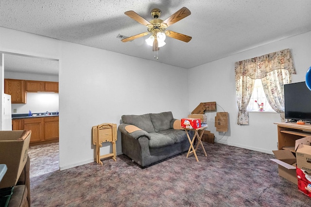 living area with ceiling fan, sink, dark carpet, and a textured ceiling