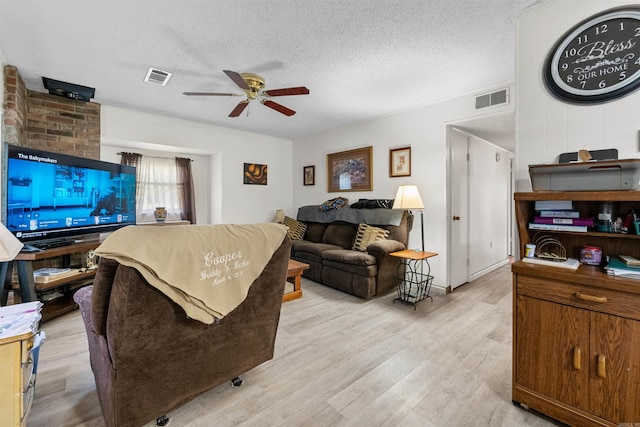 living room featuring ceiling fan, a textured ceiling, and light wood-type flooring