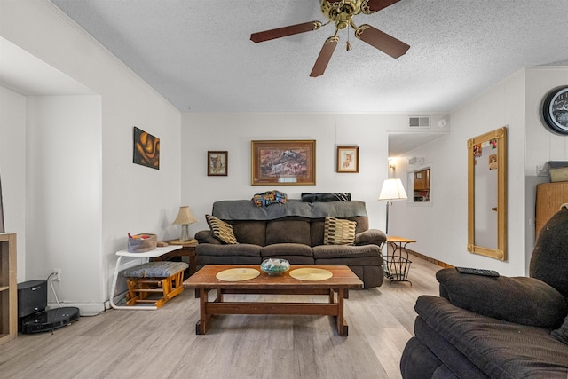 living room featuring ceiling fan, light wood-type flooring, and a textured ceiling