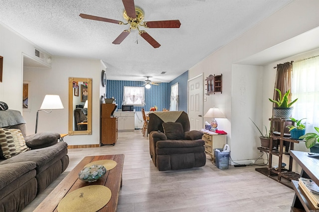 living room with ceiling fan, light hardwood / wood-style floors, and a textured ceiling