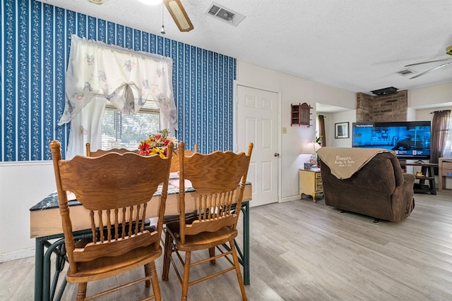 dining room with ceiling fan, a textured ceiling, and light hardwood / wood-style flooring