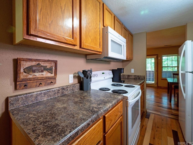 kitchen featuring white appliances, wood-type flooring, and a textured ceiling