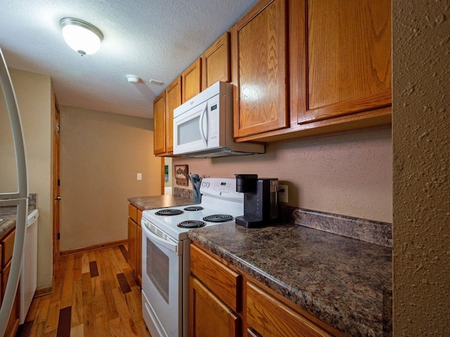 kitchen featuring white appliances, light hardwood / wood-style floors, and a textured ceiling