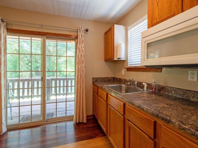 kitchen with dark wood-type flooring, sink, and dark stone countertops