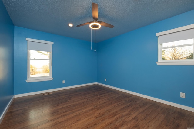 spare room with dark hardwood / wood-style flooring, ceiling fan, a wealth of natural light, and a textured ceiling