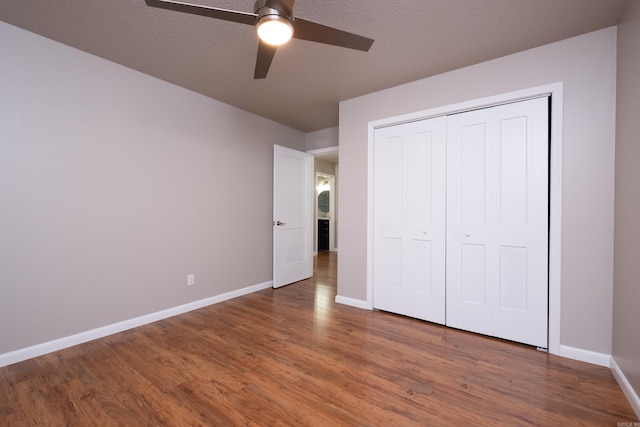 unfurnished bedroom with dark wood-type flooring, ceiling fan, a closet, and a textured ceiling