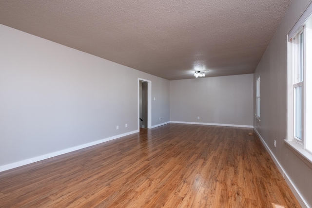 spare room with a healthy amount of sunlight, wood-type flooring, and a textured ceiling