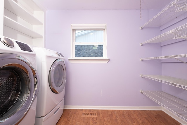 washroom featuring hardwood / wood-style flooring and washing machine and dryer