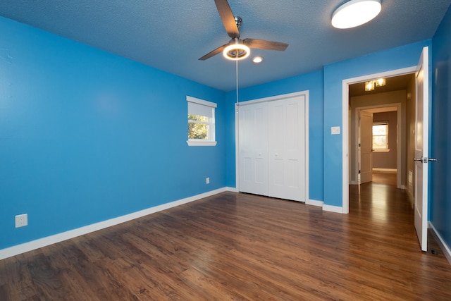 unfurnished bedroom featuring dark hardwood / wood-style flooring, a textured ceiling, ceiling fan, and a closet