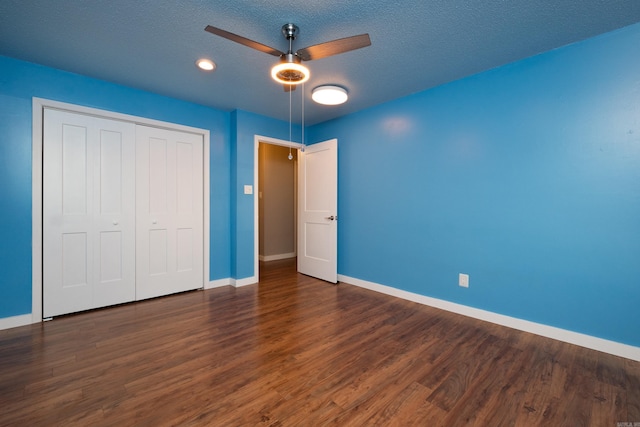 unfurnished bedroom featuring dark hardwood / wood-style flooring, a textured ceiling, ceiling fan, and a closet