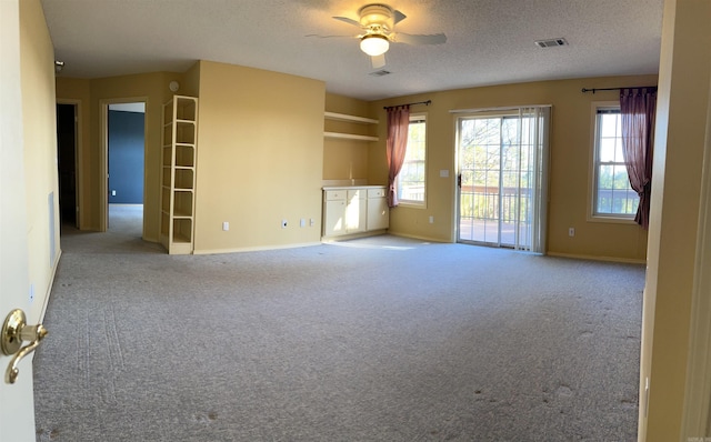 unfurnished living room with ceiling fan, light colored carpet, and a textured ceiling