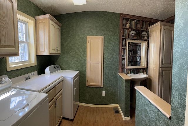 washroom with hardwood / wood-style flooring, cabinets, independent washer and dryer, and a textured ceiling