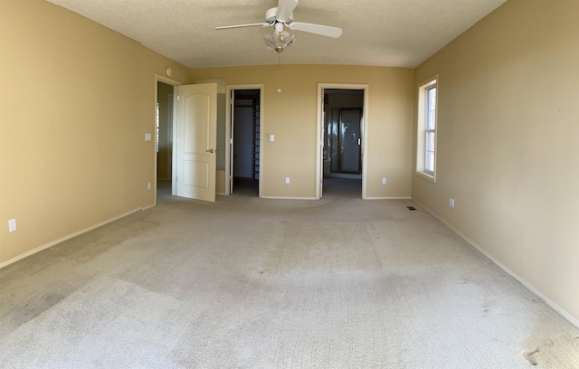 unfurnished bedroom with ensuite bath, a walk in closet, light colored carpet, and ceiling fan