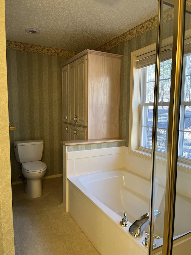 bathroom with a bath, toilet, and a textured ceiling