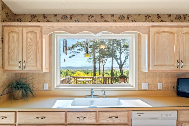 kitchen with light brown cabinetry, sink, and dishwasher