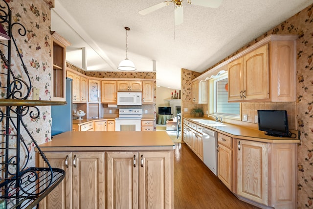 kitchen featuring sink, white appliances, vaulted ceiling, and light brown cabinets