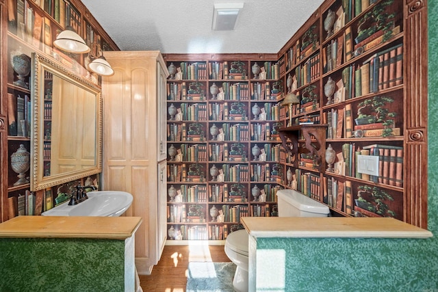 bathroom with sink, toilet, hardwood / wood-style floors, and a textured ceiling