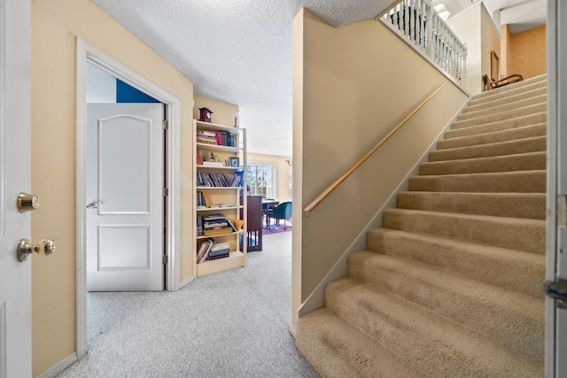 staircase featuring carpet flooring and a textured ceiling