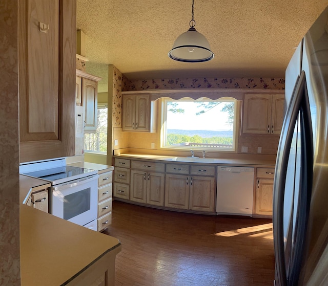 kitchen featuring hanging light fixtures, sink, light brown cabinetry, and white appliances