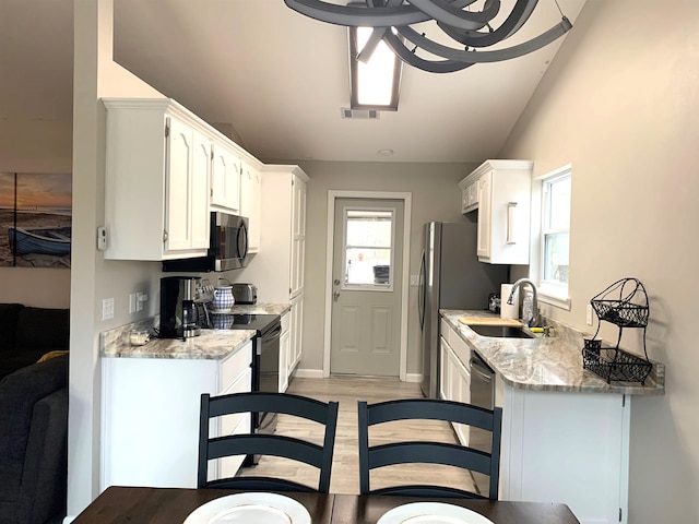 kitchen with vaulted ceiling, white cabinetry, sink, light stone counters, and electric stove