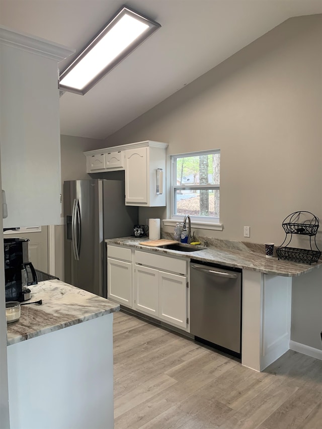 kitchen featuring lofted ceiling, appliances with stainless steel finishes, sink, and white cabinets