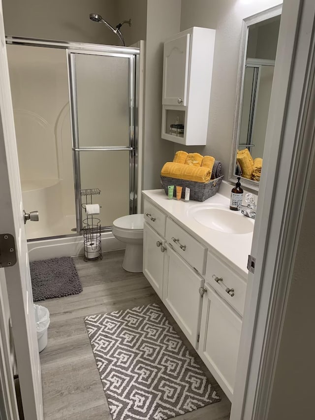 bathroom featuring hardwood / wood-style flooring, vanity, toilet, and an enclosed shower