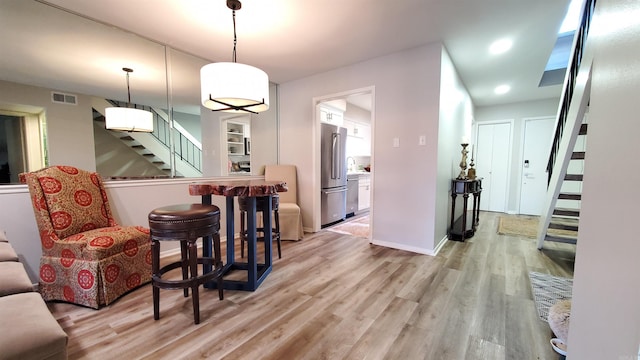 interior space featuring high quality fridge, light wood-type flooring, and decorative light fixtures